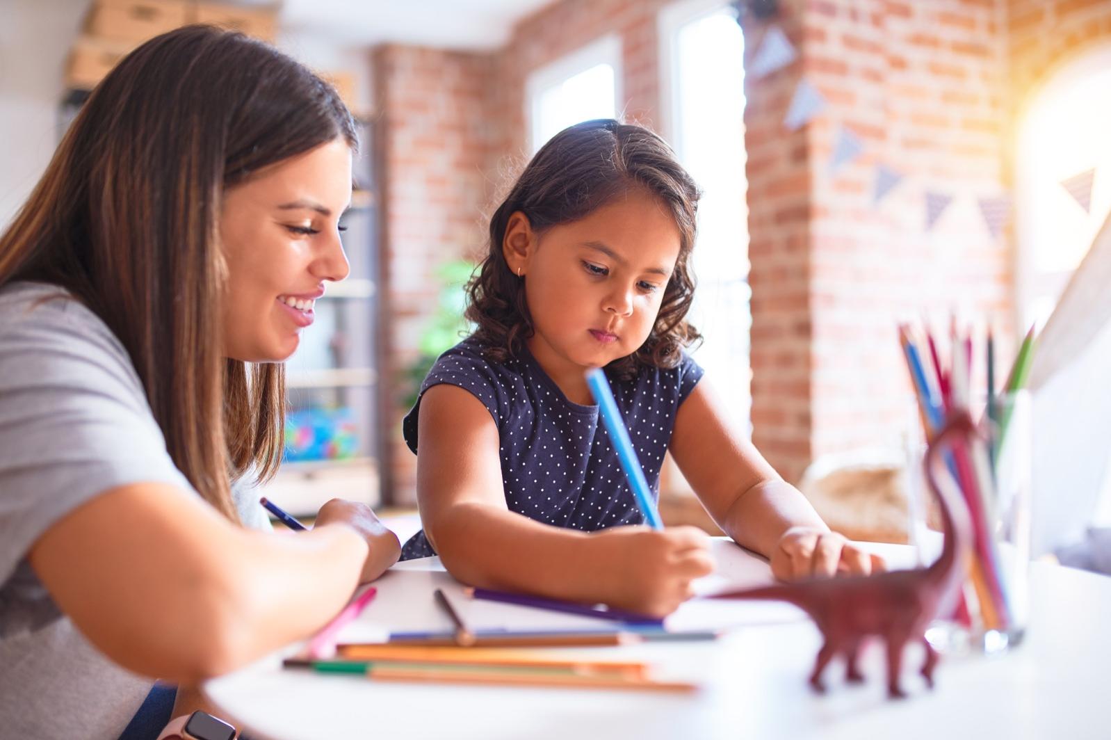 Photo of woman teaching younger student at a desk